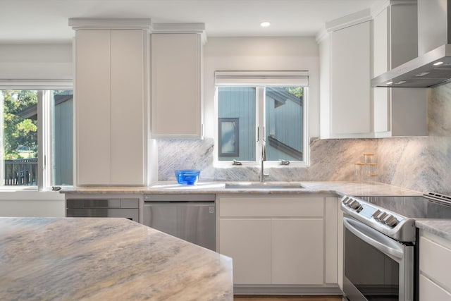 kitchen with backsplash, stainless steel appliances, a sink, and wall chimney exhaust hood