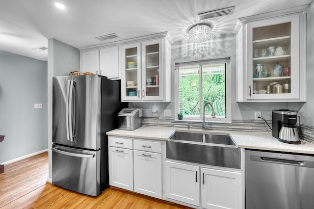 kitchen featuring sink, light hardwood / wood-style flooring, appliances with stainless steel finishes, light stone counters, and white cabinetry