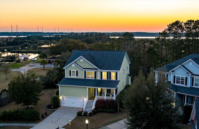 traditional home featuring concrete driveway, stairway, a garage, and roof with shingles