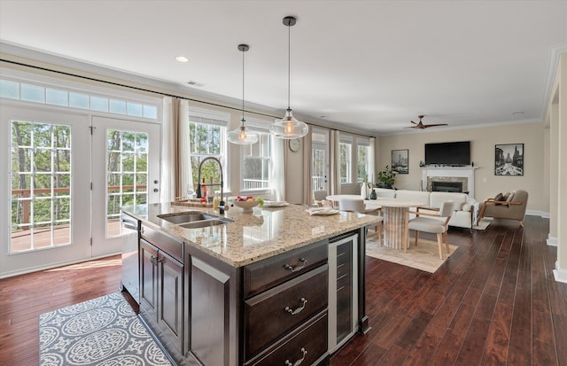 kitchen featuring a sink, beverage cooler, a fireplace, stainless steel dishwasher, and dark wood-style flooring