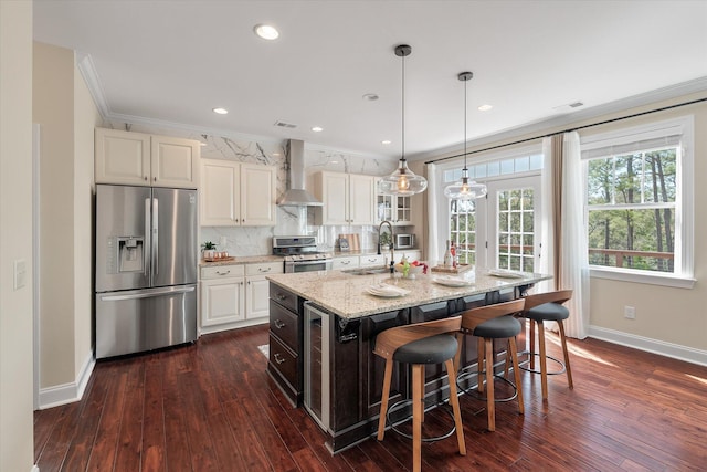 kitchen featuring ornamental molding, appliances with stainless steel finishes, a kitchen bar, wall chimney range hood, and backsplash