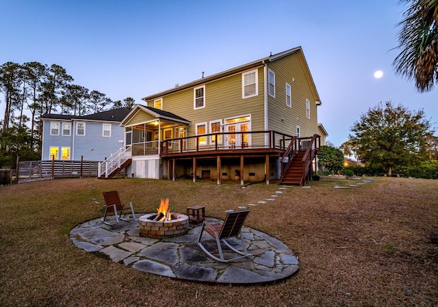 back of property with stairway, a lawn, an outdoor fire pit, and a sunroom