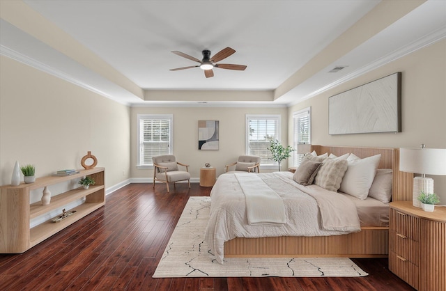 bedroom featuring baseboards, a raised ceiling, dark wood-style flooring, and crown molding