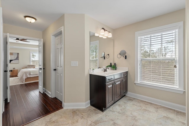 bathroom with connected bathroom, baseboards, ceiling fan, and vanity