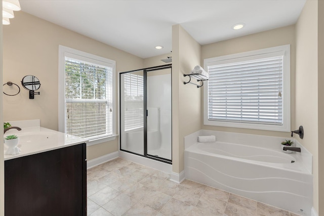 bathroom featuring a stall shower, baseboards, vanity, and a garden tub