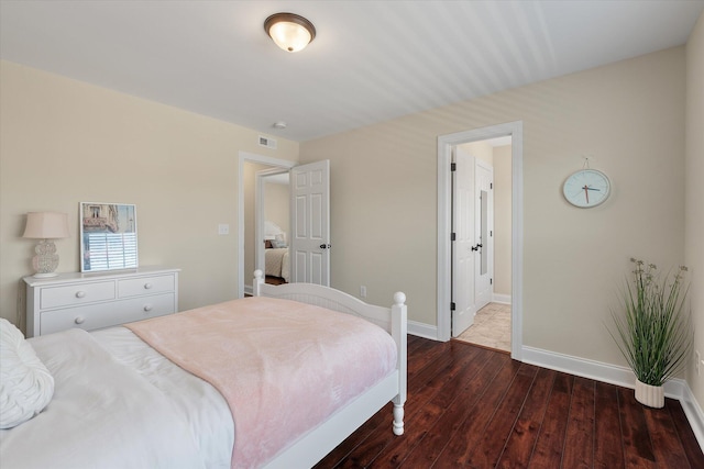 bedroom with visible vents, baseboards, and wood finished floors