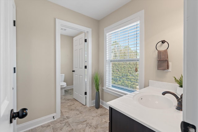 bathroom featuring toilet, vanity, and baseboards