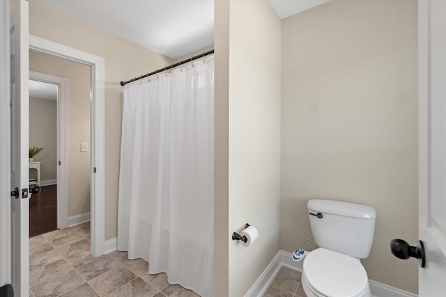 bathroom featuring a shower with shower curtain, toilet, and baseboards