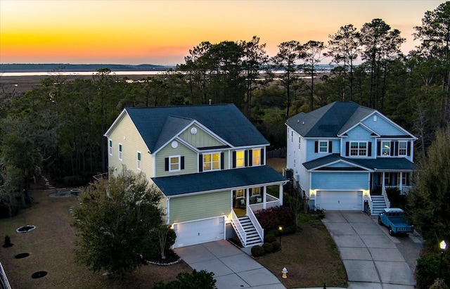 traditional-style home featuring driveway, an attached garage, and stairs