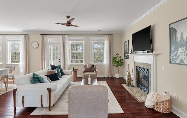 living room featuring a ceiling fan, dark wood-style floors, baseboards, a high end fireplace, and crown molding