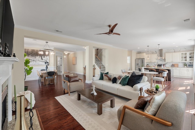 living area featuring visible vents, crown molding, stairway, a fireplace with flush hearth, and wood finished floors