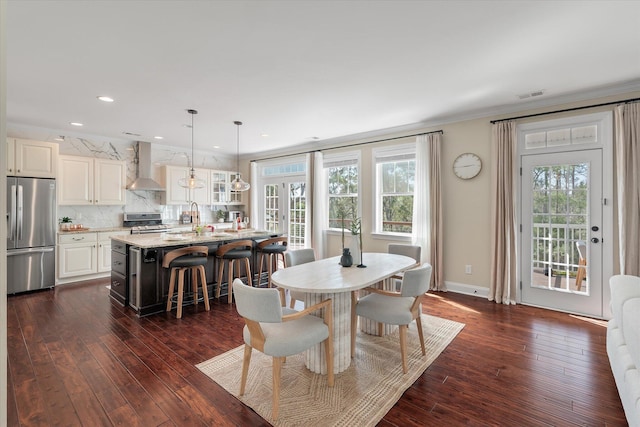 dining space featuring dark wood finished floors, crown molding, visible vents, and a wealth of natural light