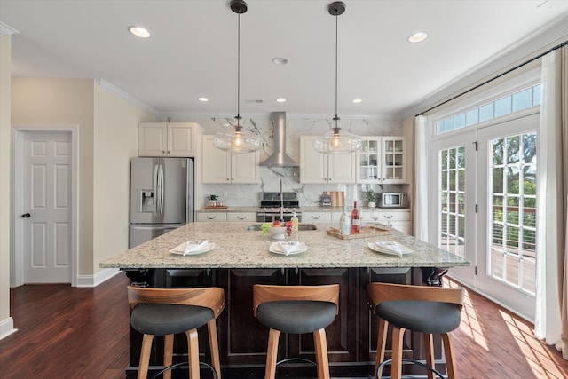 kitchen with a sink, tasteful backsplash, stainless steel appliances, crown molding, and wall chimney range hood