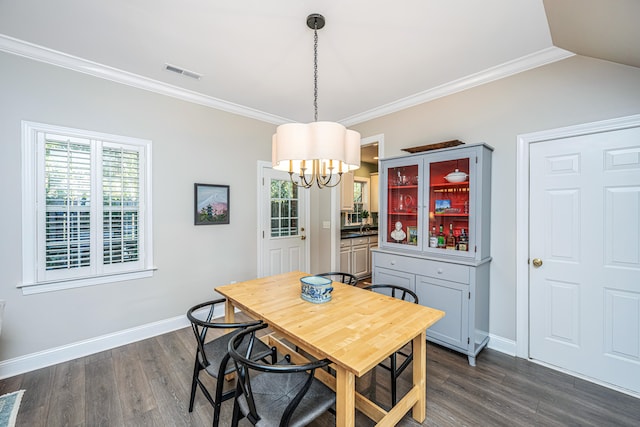 dining area with dark hardwood / wood-style floors, an inviting chandelier, and crown molding