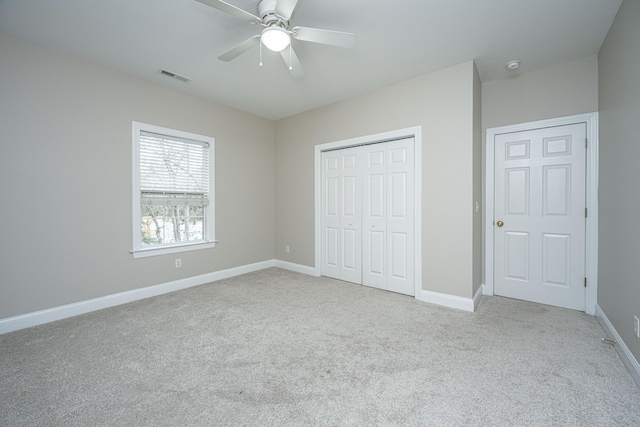 unfurnished bedroom with ceiling fan, a closet, and light carpet