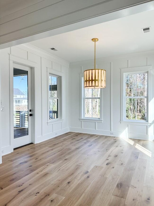 unfurnished dining area with light hardwood / wood-style floors, a healthy amount of sunlight, and crown molding