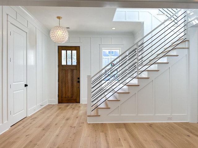 foyer with a chandelier, light hardwood / wood-style floors, and crown molding