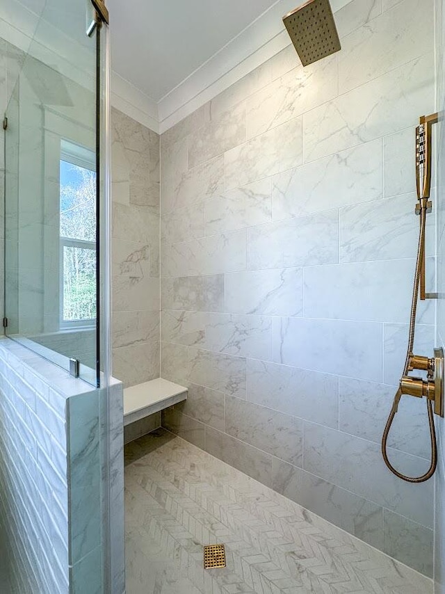 bathroom with ornamental molding and tiled shower