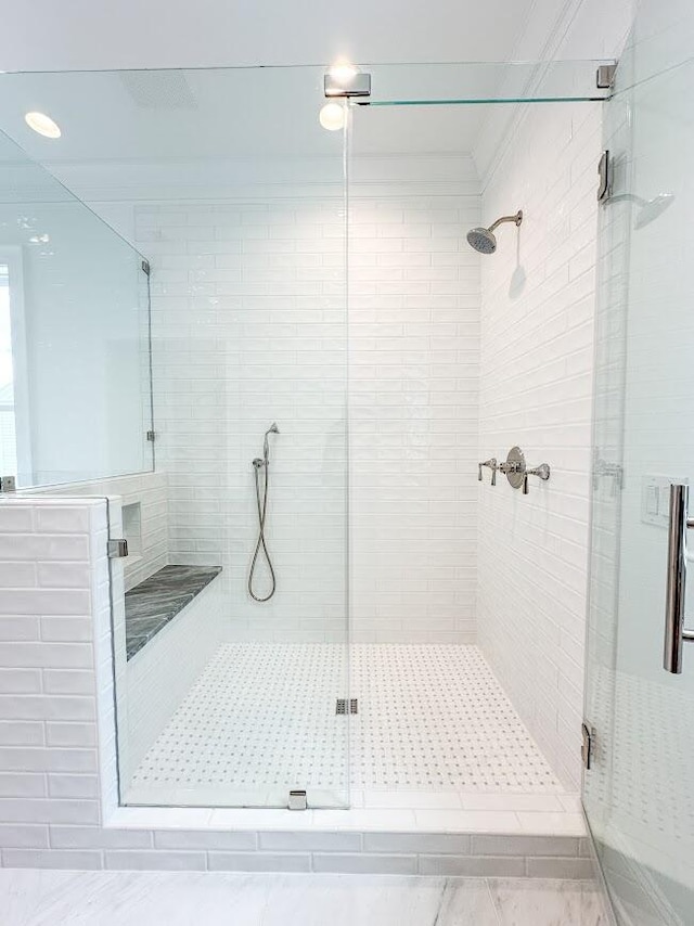 bathroom featuring ornamental molding and a shower with shower door