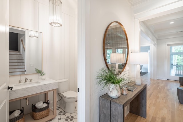 bathroom with crown molding, toilet, wood-type flooring, and sink