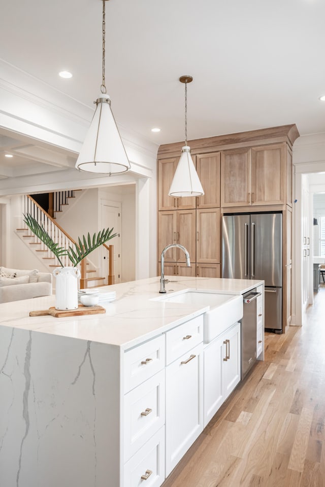 kitchen with white cabinets, pendant lighting, light wood-type flooring, and sink