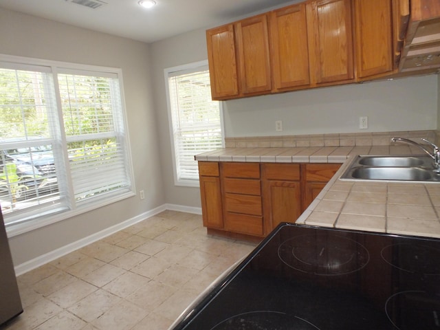418 Meritta Ave, Beaufort, SC 29902 - kitchen with a sink, tile countertops, baseboards, brown cabinetry, and cooktop