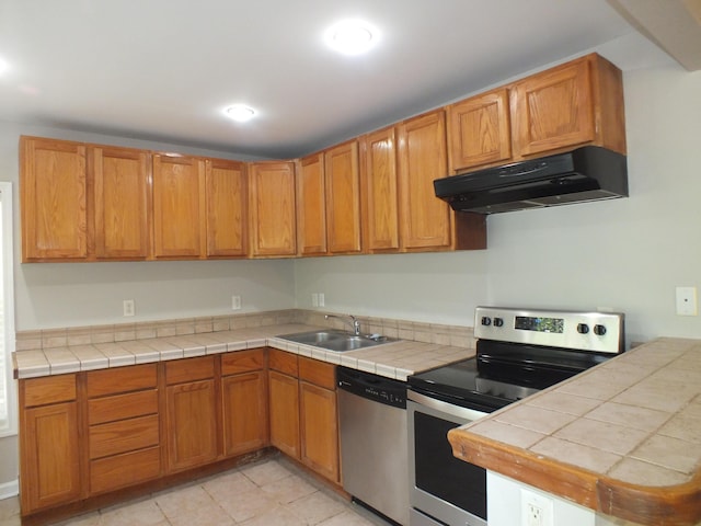 418 Meritta Ave, Beaufort, SC 29902 - kitchen with under cabinet range hood, stainless steel appliances, a sink, brown cabinetry, and light tile patterned floors