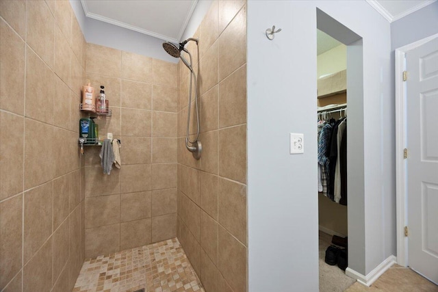 full bath featuring a walk in closet, crown molding, baseboards, and tiled shower