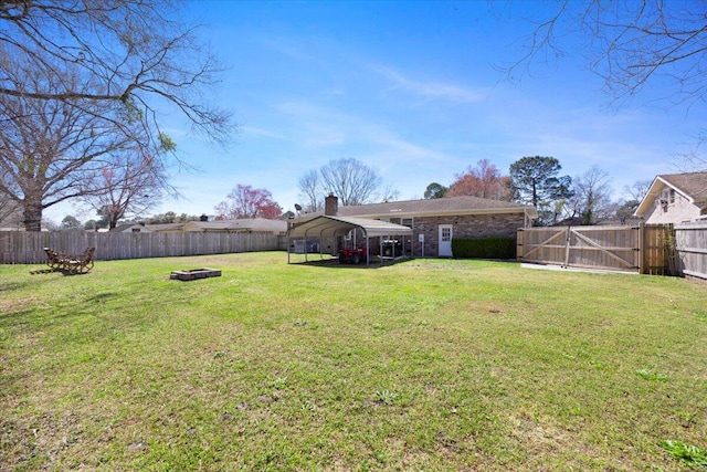 view of yard featuring a carport, a fenced backyard, and a gate