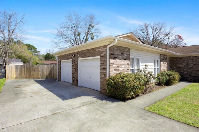 exterior space with concrete driveway, a garage, fence, and brick siding