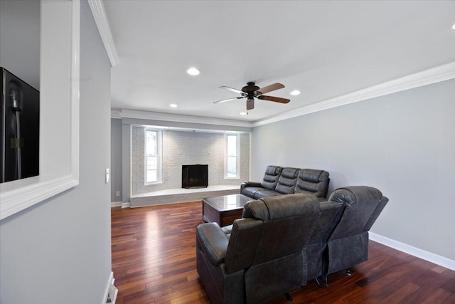 living area with baseboards, a ceiling fan, dark wood finished floors, and crown molding