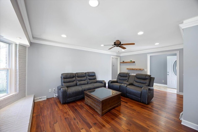 living area featuring visible vents, dark wood-type flooring, ornamental molding, and a ceiling fan