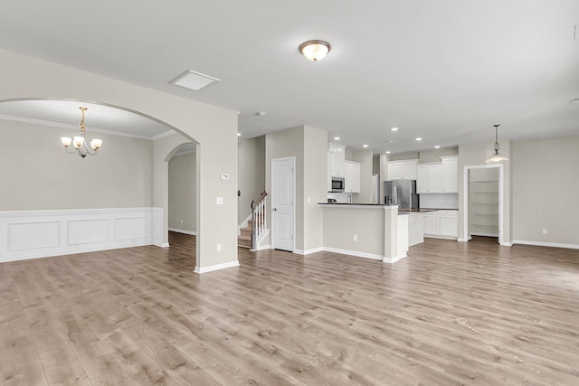 5138 Preserve Blvd, Ladson, SC 29456 - unfurnished living room with light wood-style floors, ornamental molding, stairway, wainscoting, and arched walkways