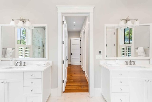 bathroom with baseboards, two vanities, marble finish floor, and a sink