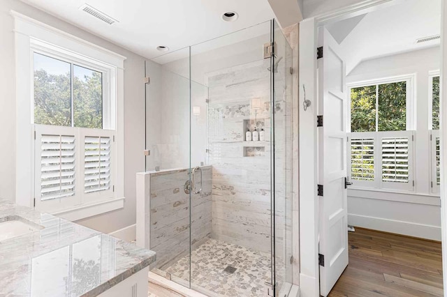 full bath featuring visible vents, a shower stall, wood finished floors, and a healthy amount of sunlight
