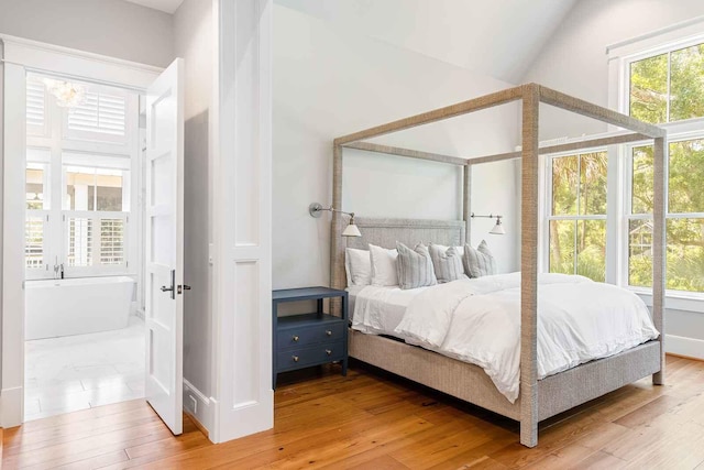 bedroom with lofted ceiling, hardwood / wood-style flooring, and a notable chandelier
