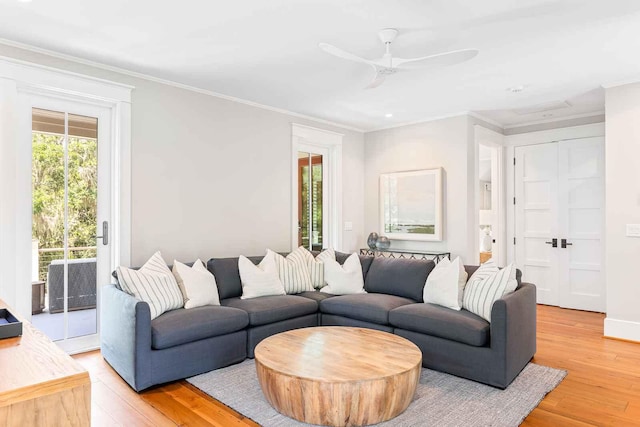 living area featuring crown molding, light wood-style flooring, and a ceiling fan