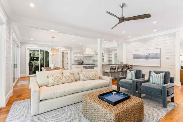 living area featuring recessed lighting, ornamental molding, ceiling fan, and light wood-style flooring