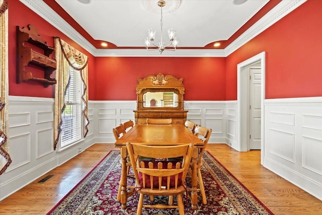 dining space featuring a chandelier, crown molding, a wainscoted wall, wood finished floors, and recessed lighting