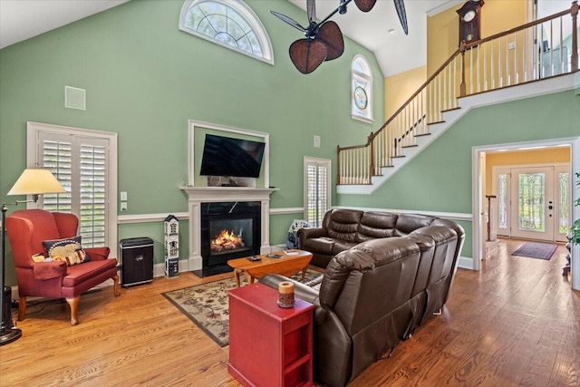 living room with high vaulted ceiling, ceiling fan, wood finished floors, and plenty of natural light