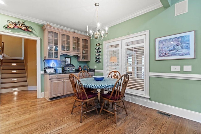 dining room with ornamental molding, a chandelier, light wood-type flooring, stairway, and baseboards