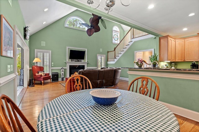 dining area with stairway, a warm lit fireplace, light wood-style flooring, recessed lighting, and baseboards