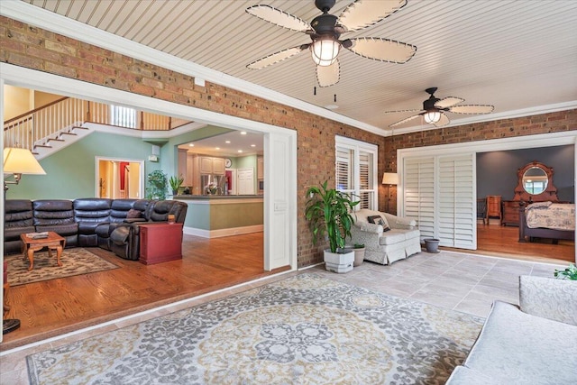 living area with a ceiling fan, stairs, crown molding, and light wood-type flooring