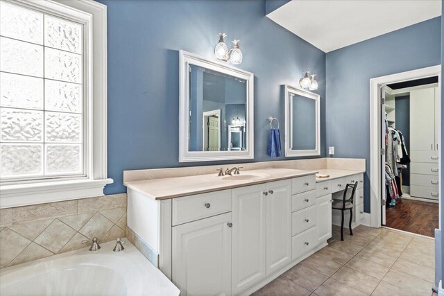 bathroom with healthy amount of natural light, vanity, tile patterned flooring, and a garden tub