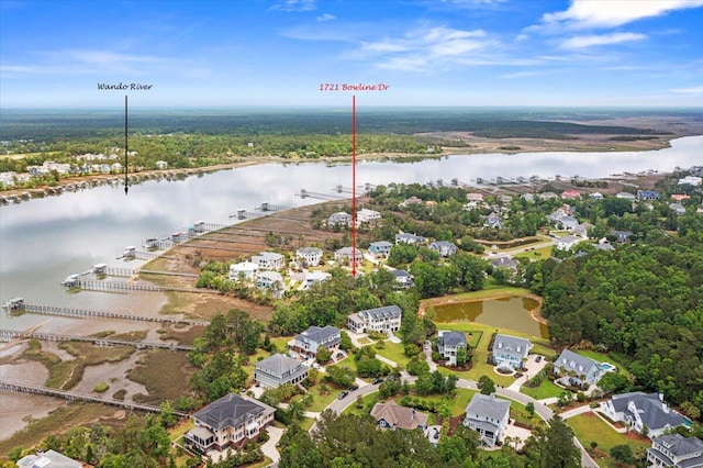 aerial view of property and surrounding area featuring a nearby body of water, nearby suburban area, and a forest