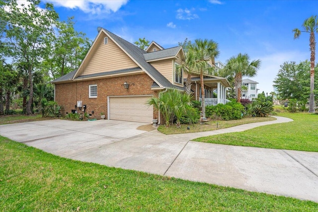 view of side of home with a garage, a lawn, driveway, brick siding, and covered porch