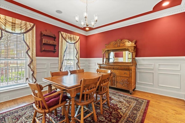 dining area with plenty of natural light, a chandelier, wainscoting, crown molding, and wood finished floors