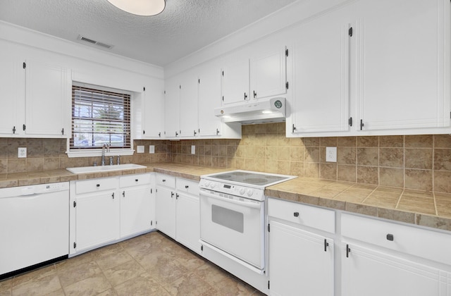 kitchen featuring visible vents, under cabinet range hood, a sink, white cabinetry, and white appliances