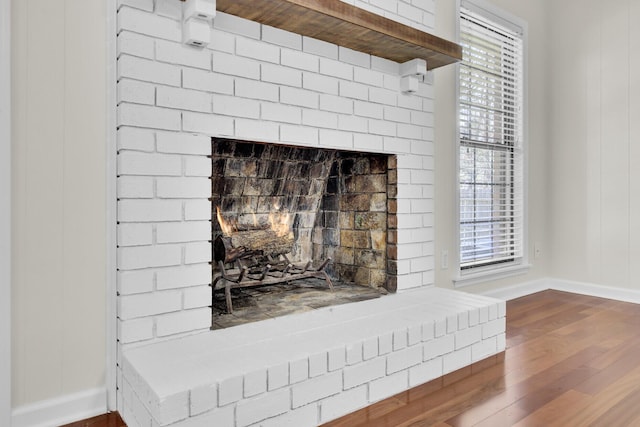 interior details featuring baseboards, a brick fireplace, and wood finished floors