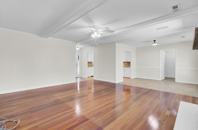 unfurnished living room featuring visible vents, baseboards, beamed ceiling, light wood-style flooring, and a ceiling fan